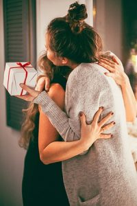 Women hugging and holding gift at holiday party