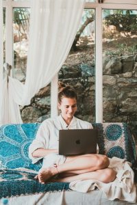 Woman on sofa looking at laptop in bohemian room